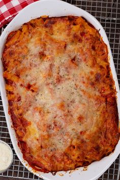 a casserole dish with cheese and sauce in it on a cooling rack next to a spoon