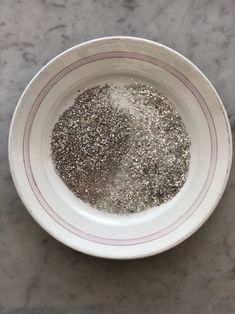 a white bowl filled with silver glitter on top of a marble countertop next to a knife and fork