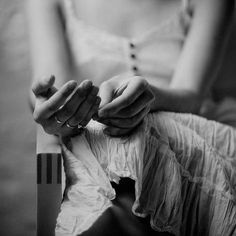 black and white photograph of a woman's hands holding a piece of paper while sitting on a chair