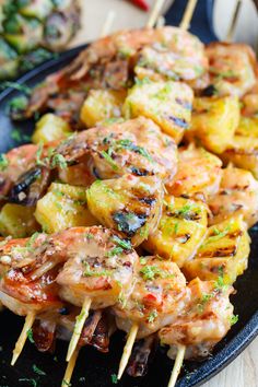 grilled shrimp and pineapple kabobs on a black plate with toothpicks