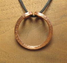 "This is a stout, but not overly heavy, pendant.  The copper is 6 gauge copper wire, flattened slightly and textured, 99.99% pure copper.  The pendant is 1.8\" (46 mm) diameter.  It is about 19 grams. A 1/4\" diameter rod will fit through the hole, easily allowing a clasp to pass through, if you wish to use your own cord or chain. The cord is silky nylon, very smooth and very strong, 2.5 mm thick and adjustable. I have been working with metals for 30 years and copper is still a mystery to me at Handmade Round Jewelry With Waxed Cord, Hand Forged Copper Round Pendant Necklace, Adjustable Copper Wire Necklace With Round Pendant, Artisan Black Copper Necklace, Antique Finish Copper Round Pendant Necklace, One-of-a-kind Copper Round Pendant Jewelry, Copper Pendant, Copper Rings, Copper Pendants