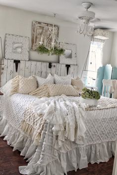 a white bed with ruffled bedspread and pillows on top of it in a bedroom