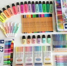 many different colored markers and pencils are laid out on a white surface next to each other