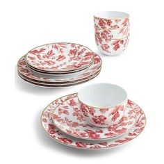 four red and white china cups and saucers with floral designs on the rims