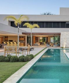 an outdoor swimming pool in front of a large house with lounge chairs and palm trees