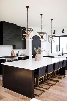 a large kitchen with black cabinets and white counter tops, an island in the middle