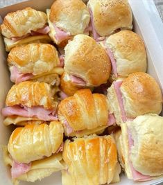 a box filled with lots of different types of sandwiches and pastries on top of each other