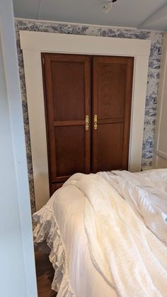 a bedroom with two wooden doors and a white bed