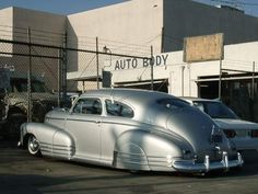 an old silver car parked in front of a building