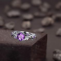 a ring with an amethyst purple stone in the center and leaves around it