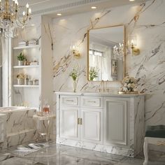 a bathroom with marble walls and flooring, chandelier, mirror, sink and bathtub