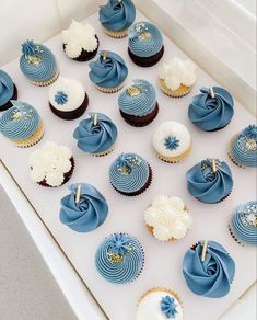 blue and white cupcakes are arranged in a box