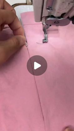 someone is using a sewing machine to sew on pink fabric with the help of a needle