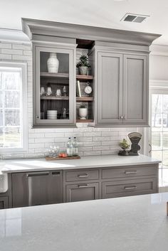 a kitchen with gray cabinets and white counter tops