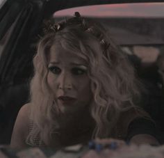 a woman sitting in the back seat of a car wearing a crown on her head