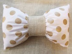 a white and gold polka dot bow tie on a couch with a brown pillow behind it