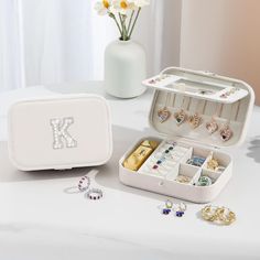 an open jewelry box sitting on top of a table next to a vase with flowers