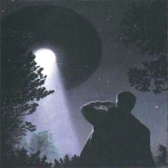 a man standing next to a tree under a light in the night sky with his head down