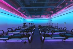 a room filled with lots of black and blue chairs next to a wall covered in neon lights