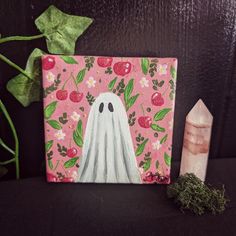 a painting of a ghost on a pink background next to a crystal point and plant