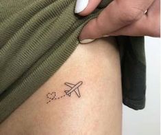 a woman's leg with a small airplane tattoo on the back of her thigh