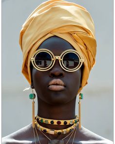 an african woman wearing sunglasses and a turban with gold chains on her head