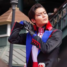 a woman dressed in black and red is holding her hands on her chest while wearing gloves