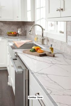 a kitchen with marble counter tops and white cabinets, along with stainless steel sink faucets