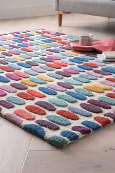 a colorful rug on the floor in a living room with a couch and coffee cup