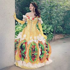 a woman in a yellow dress standing next to a wall with the words tacobelle on it