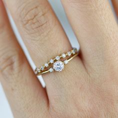 a woman's hand with a diamond ring on top of her finger and an engagement band