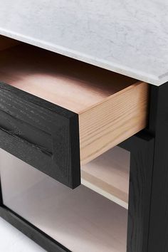 an open drawer on the side of a wooden cabinet with marble top and bottom panel