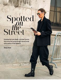 a woman is walking down the street while looking at her cell phone and wearing all black