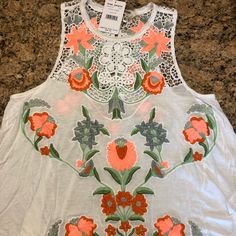 Brand New With Tags Women's Free People Brand $98 Retail White Flowy Tank Top Floral Design Size Medium White Tank Top For Spring And Summer, White Floral Embroidery Tank Top For Spring, White Embroidered Tank Top For Spring, Casual White Tank Top With Floral Embroidery, Spring White Tank Top With Floral Embroidery, White Floral Embroidered Tank Top For Vacation, White Stretch Floral Print Tank Top, Casual Floral Embroidered Sleeveless Tank Top, White V-neck Tank Top With Floral Print