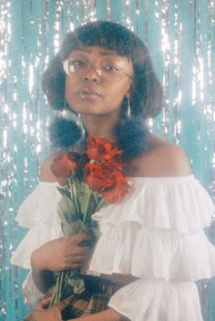 a woman holding a bouquet of flowers in front of a blue background with sequins