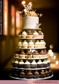 a wedding cake is stacked with cupcakes