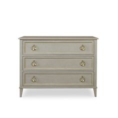 a white dresser with three drawers and two gold knobs on the bottom, against a white background