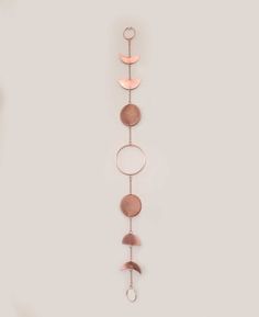 a metal wall hanging with circles and moon shapes on it's sides, in front of a white background