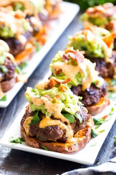 three white plates topped with mini burgers covered in guacamole and other toppings