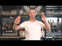 a man standing in front of a bar holding his hands up