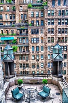 an outdoor patio with chairs and tables surrounded by tall buildings