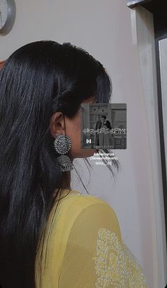 a woman with long black hair wearing earrings