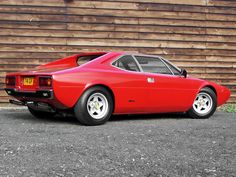 a red sports car parked in front of a wooden building