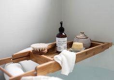 a wooden tray with soap, toothbrush and other items on it in a bathroom