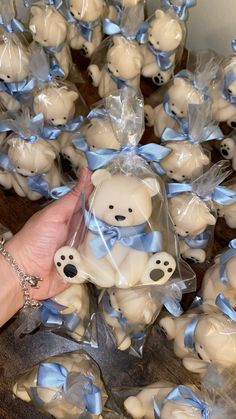 a hand holding a bag full of small teddy bears with blue ribbons on them, all wrapped in clear cellophane