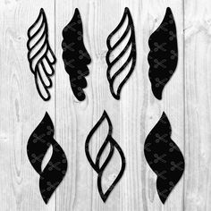 four black and white paper cut outs with different shapes on wooden background, including leaves