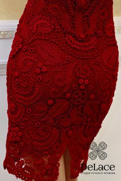 a woman is wearing a red dress with an intricate lace design on the bottom and side