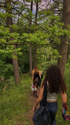 two women walking down a trail in the woods with backpacks on their back legs