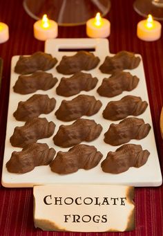 chocolate frosted frogs on a white plate with lit candles in the backgroud