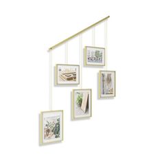 an assortment of framed pictures hanging on a wall with gold metal bar and white frame